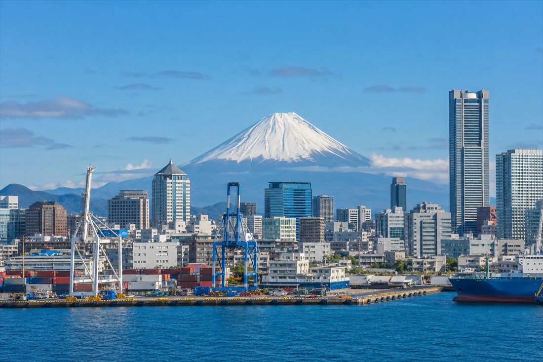 Japanese harbour city skyline with cargo cranes and Mount Fuji in the distance
